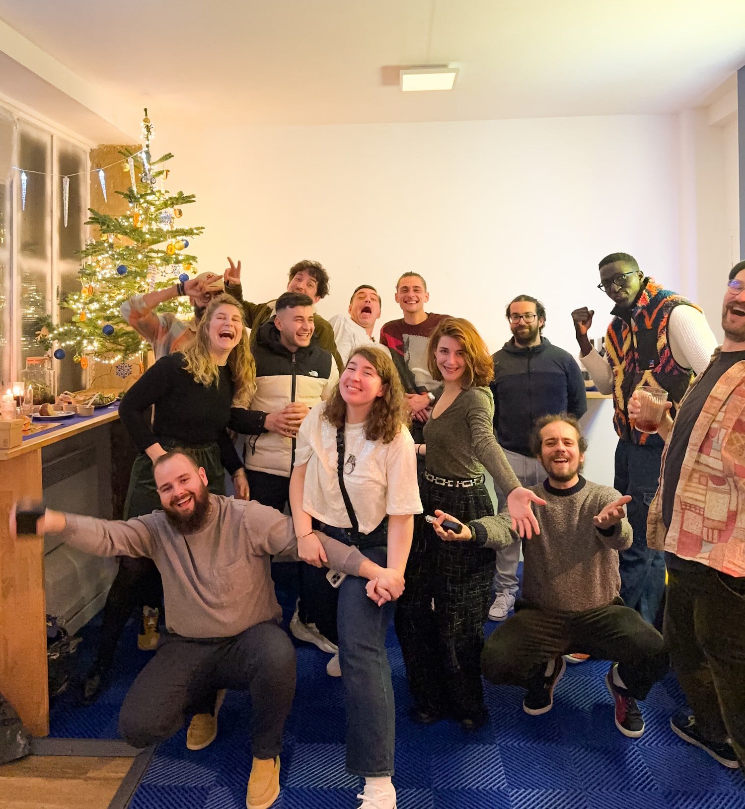 L'équipe Springare au complet, bras levés et sourires, devant le sapin de Noël du hub