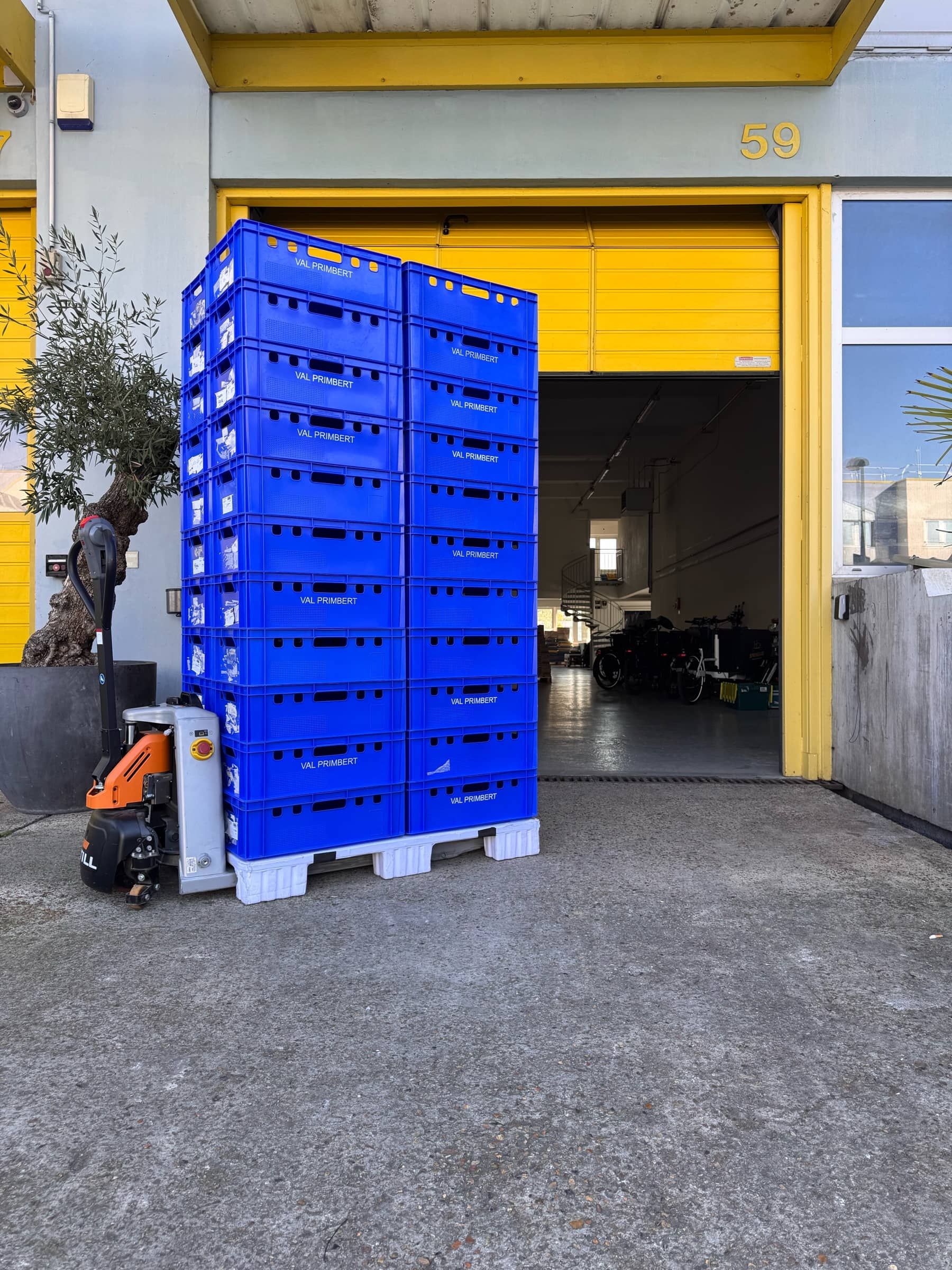 Deux colonnes de caisses bleues sur une palette, devant le quai de l'entrepôt Springare à Cap 18