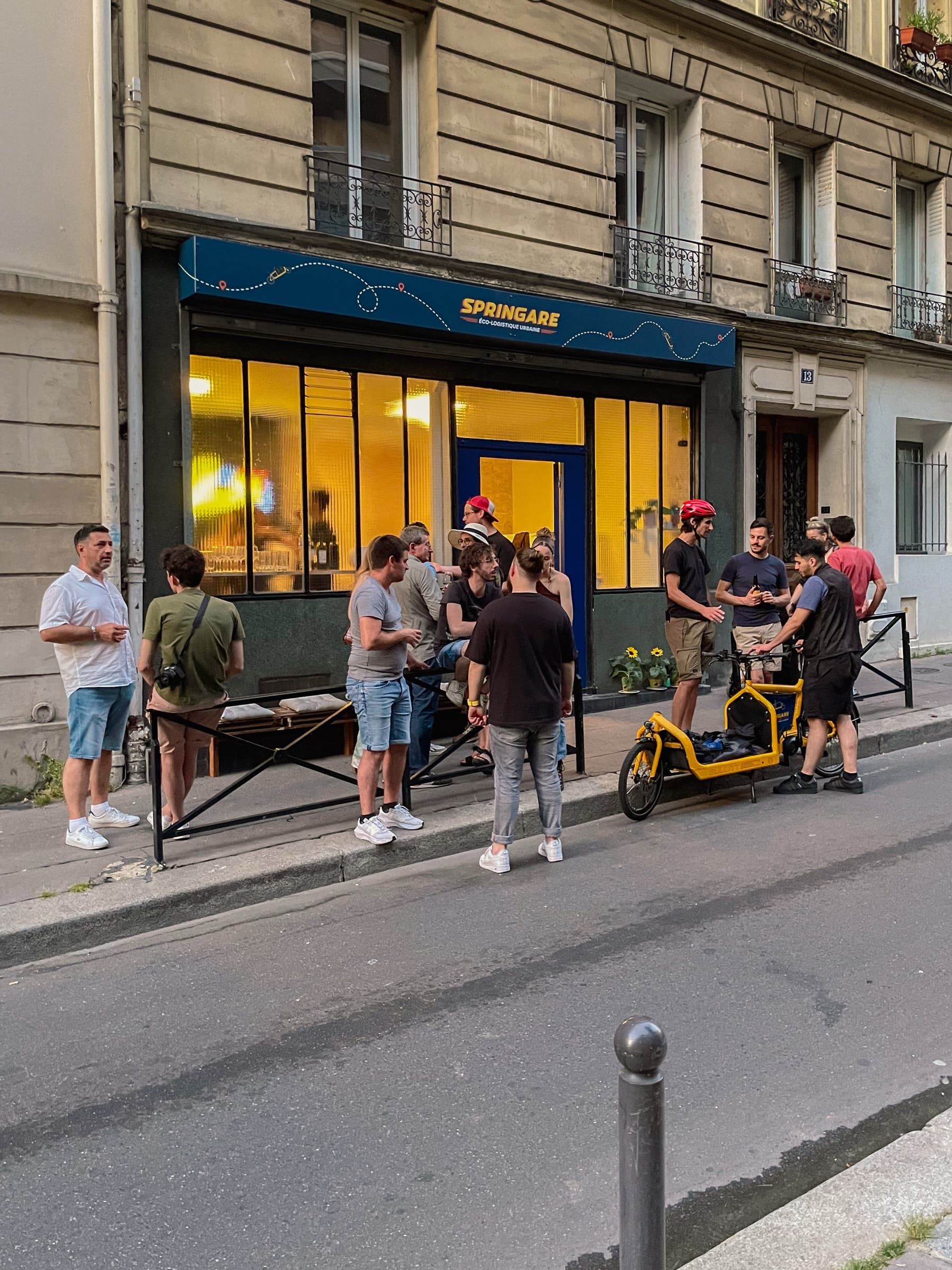 L'équipe Springare rassemblée sur le trottoir devant la boutique, un vélo cargo jaune garé le long de la chaussée